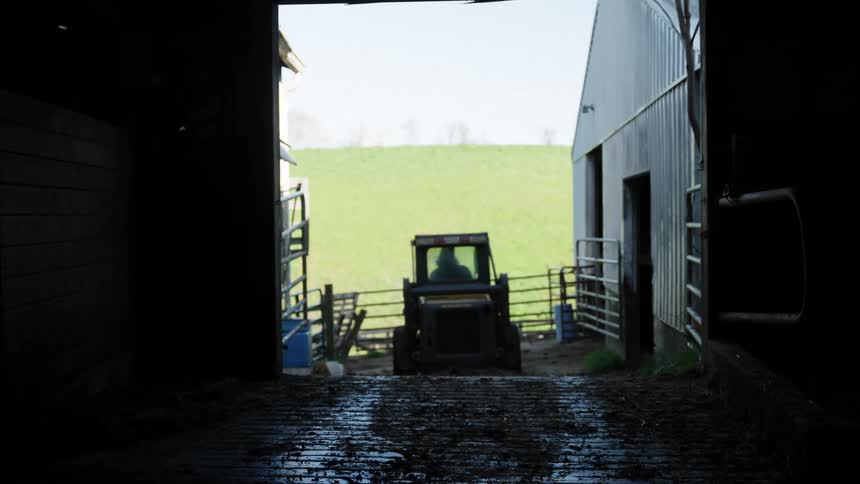 Small tractor leaving a farm shed