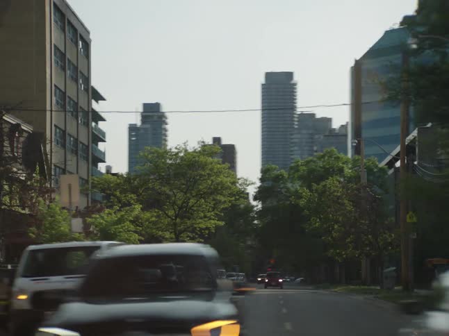 City streets and skyscrapers on a sunny day seen from a moving vehicle