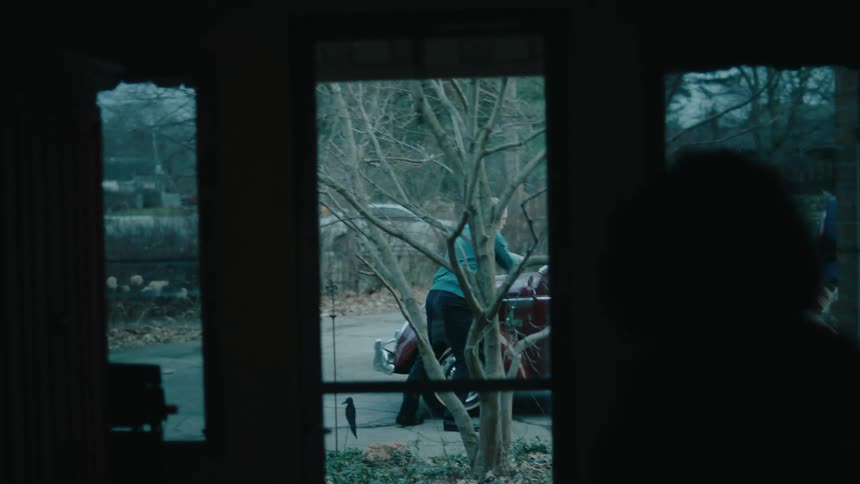 A group of people stops a red volkswagen outside a building