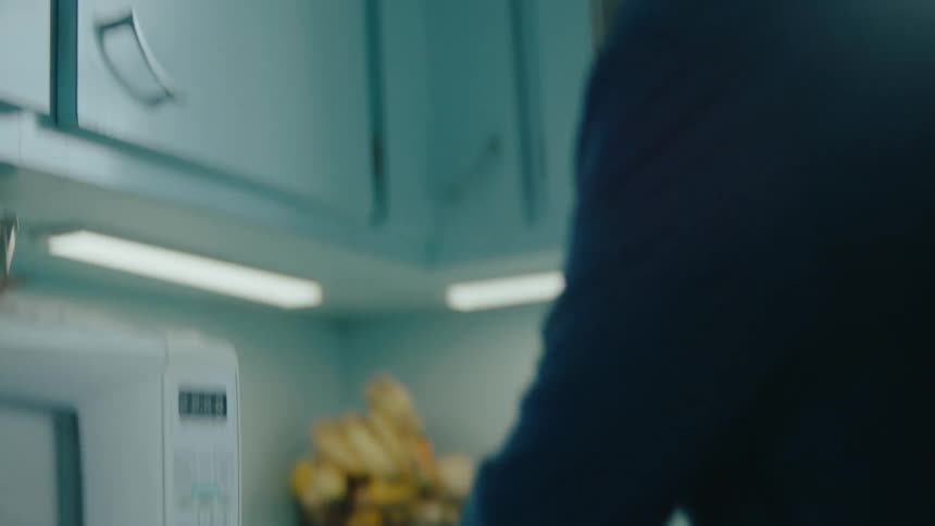 Elderly lady walking into the kitchen and picking up a food storage
