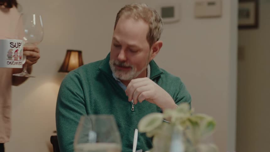 A woman walks past a man with a wine glass