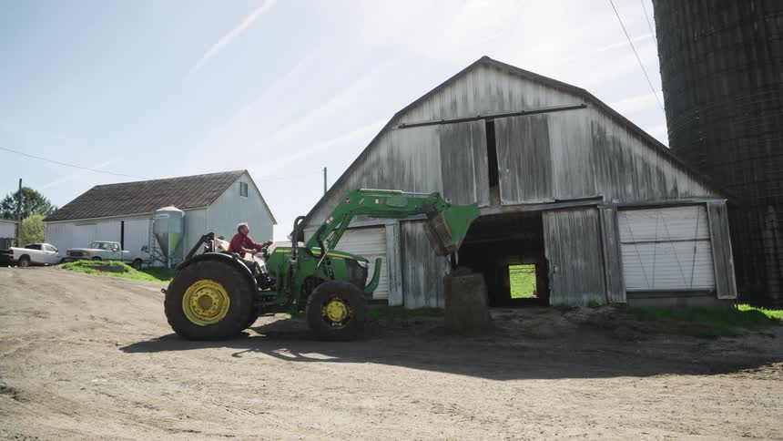 A man is operating a tractor near the barn