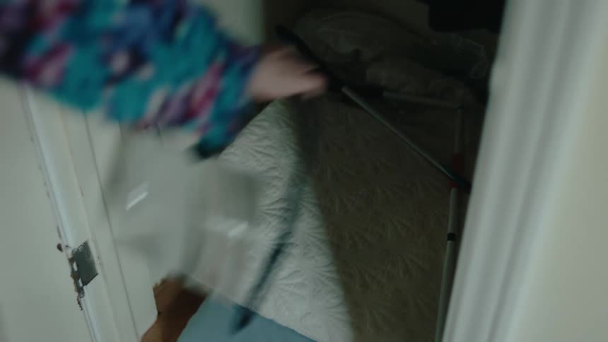 A woman opens a closet door and throws her purse on top of a quilt