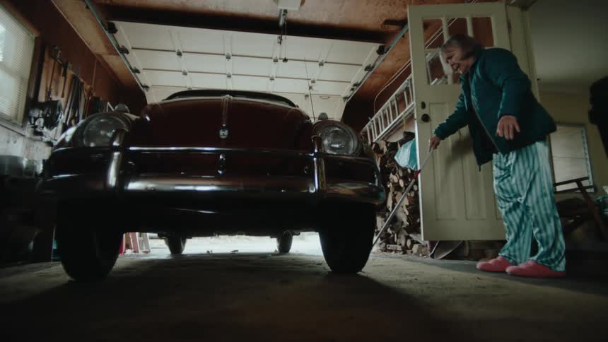 The elderly woman walks to her car in the garage