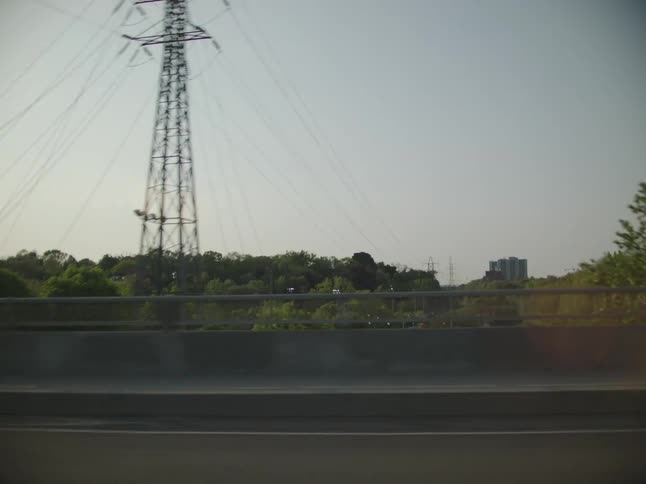 Electric power tower next to a highway with metropolis buildings in the background