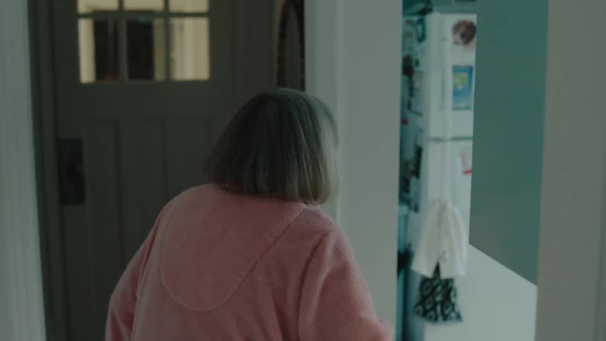 Elderly woman walking towards the kitchen leaning on the walls
