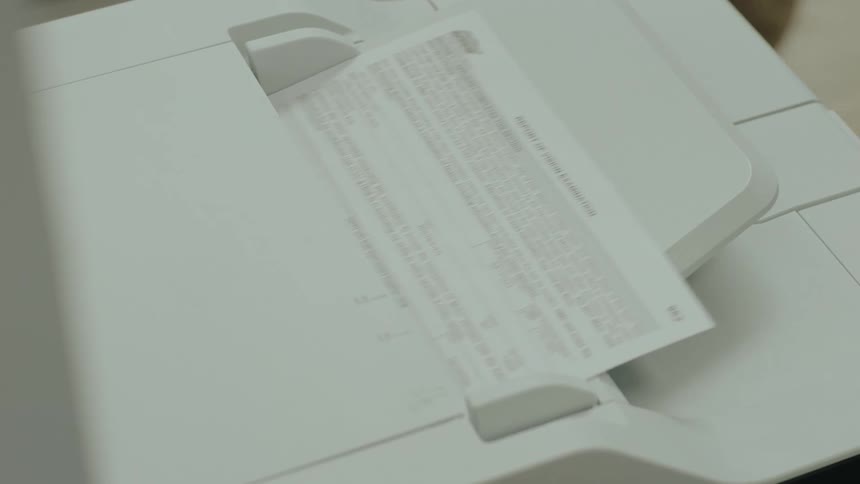 Close up of people trying to stop a paper to enter a printer