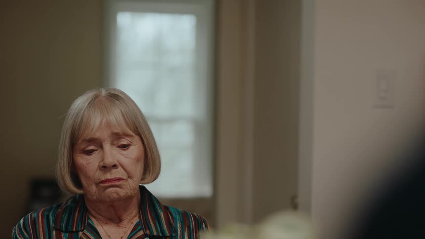 A sad looking elderly female in a house looking around
