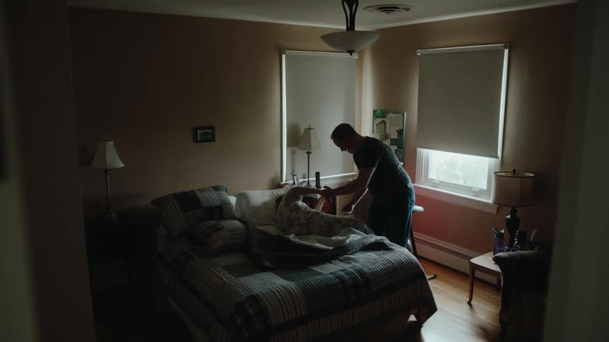 A man helps an elderly woman out of bed
