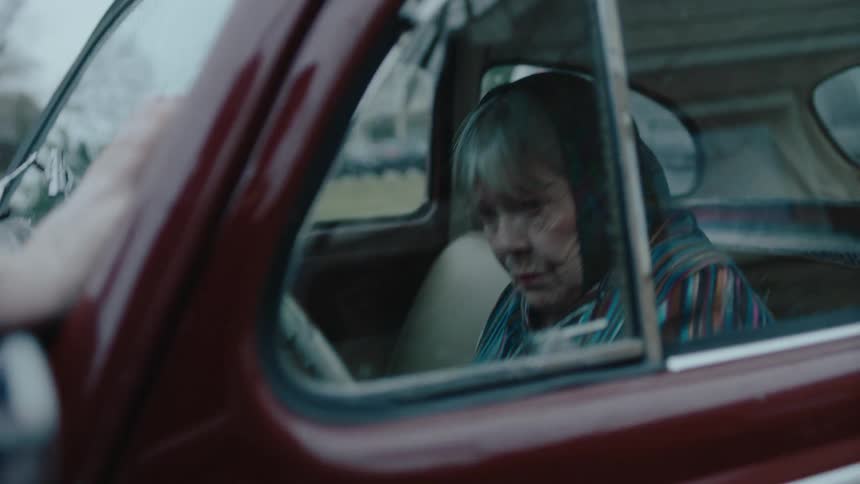 An elderly woman is trying to drive a car