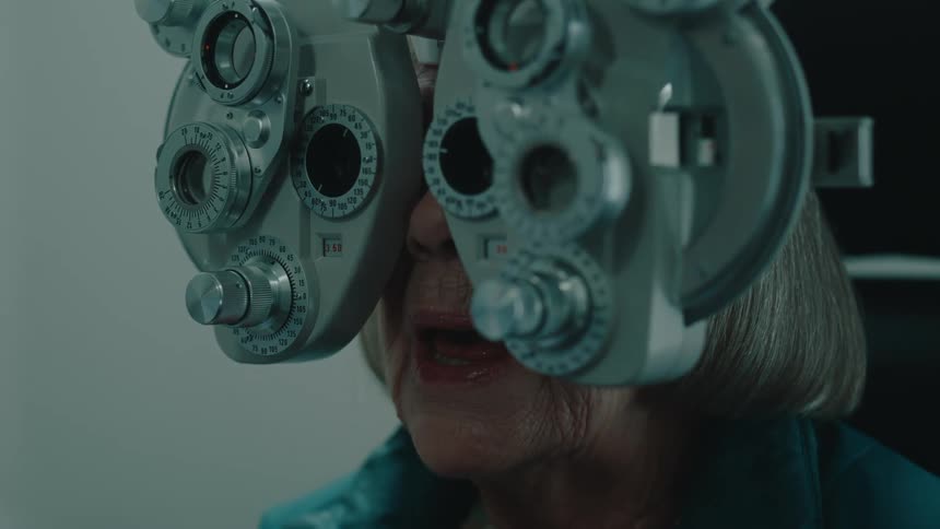 Elderly woman performing an eye exam with a phoropter