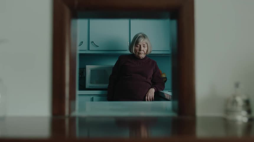 Mirror reflects elderly woman dropping a toy car in the kitchen and crouching to pick it up