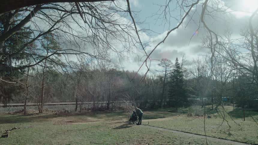 A man moves a woman in a wheelchair outdoors