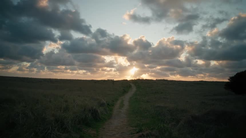 A wide open rural field landscape on a cloudy day at sunset
