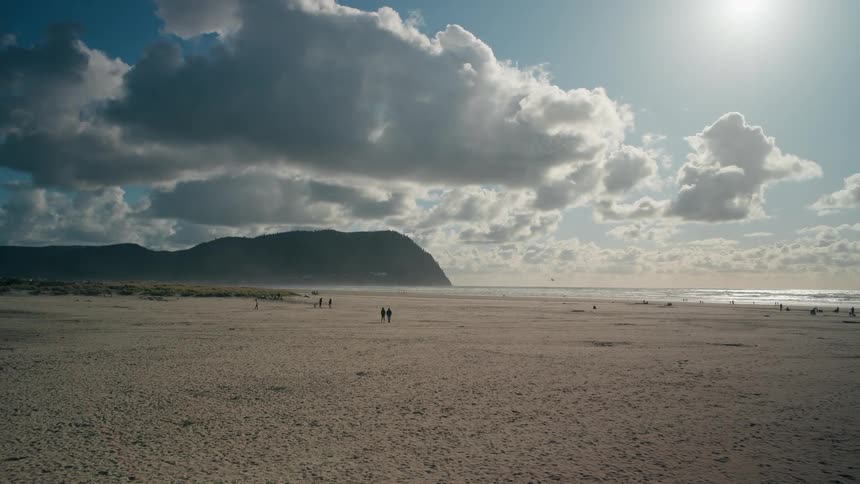 Beach with a long stretch of sand and the sea coast in the background on a sunny day with clouds