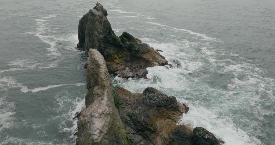 Aerial of waves crashing on two large rock formations in the ocean