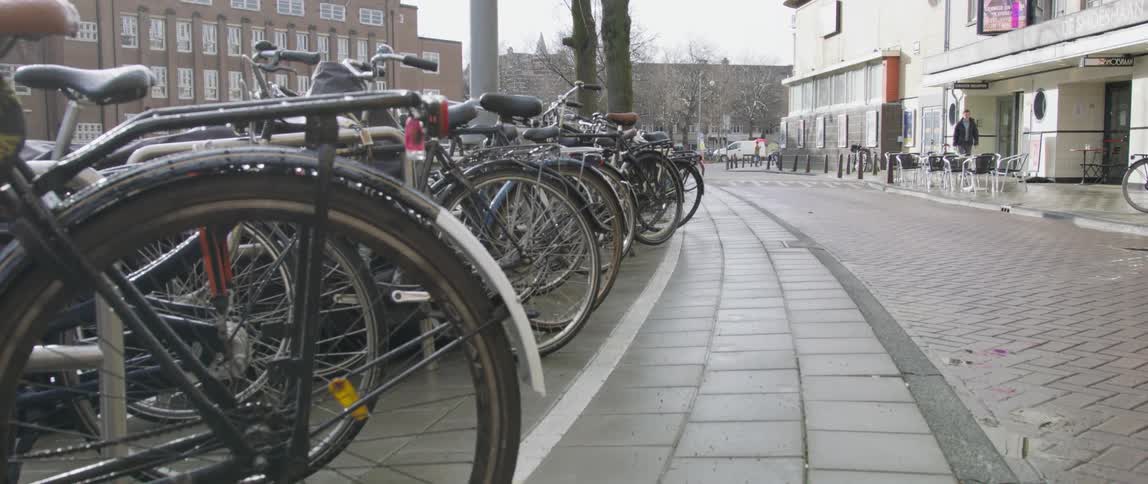 Bicycles lined up on racks in a nearly deserted downtown on a rainy day