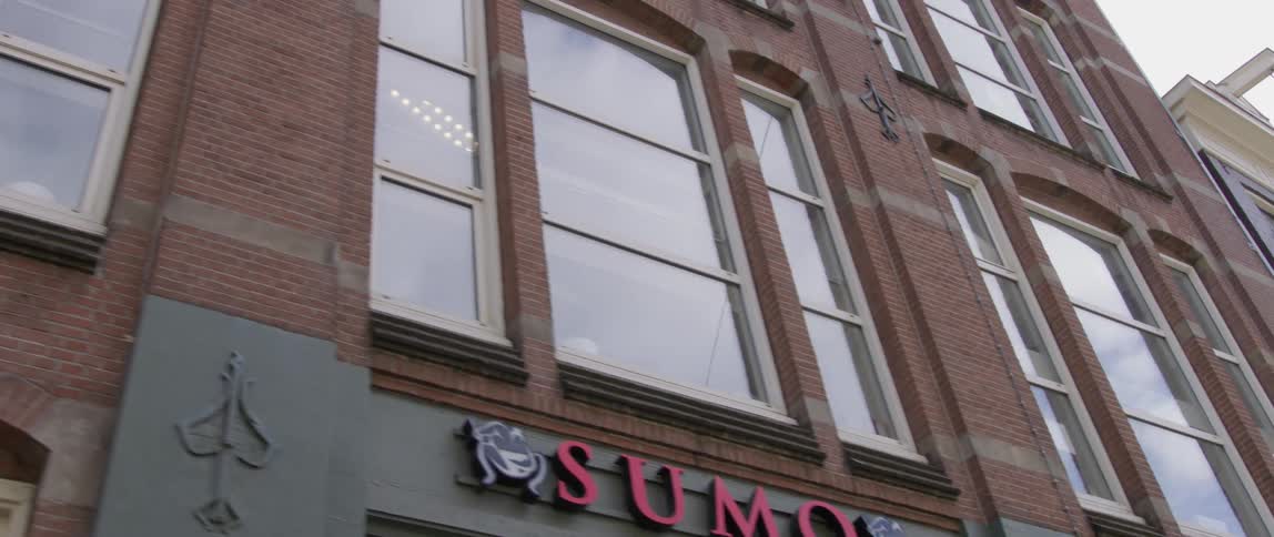 Pedestrian walks past mid rise buildings on a sunny day