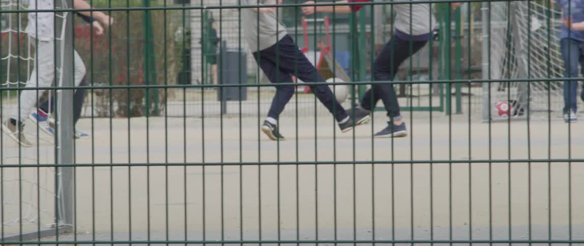 Legs of boys playing soccer on a court