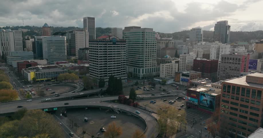 A cityscape with modern buildings roads and vehicles under an overcast sky