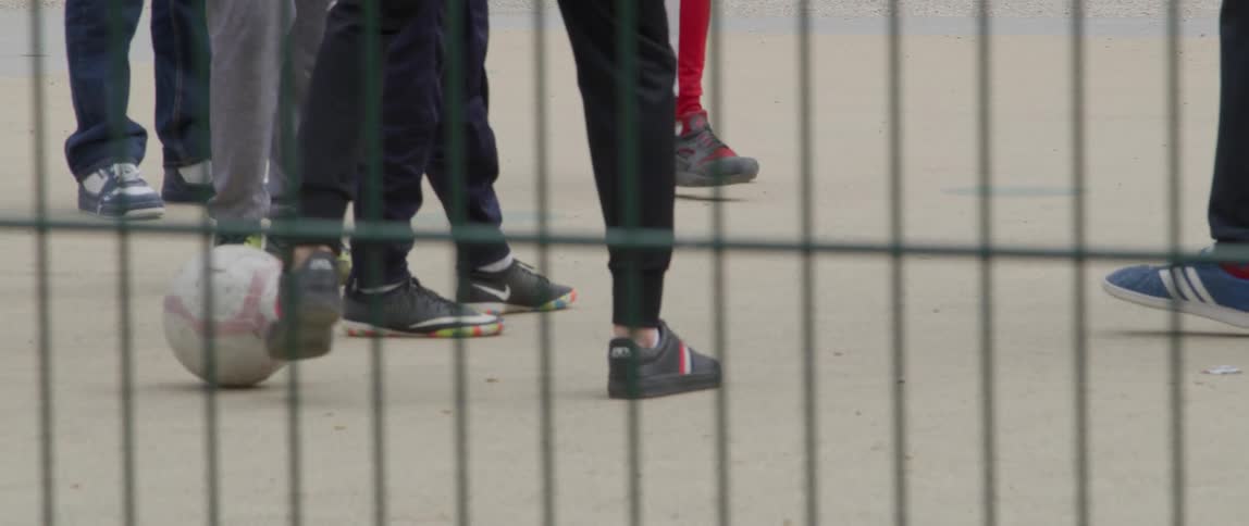 People behind a metal fence playing soccer