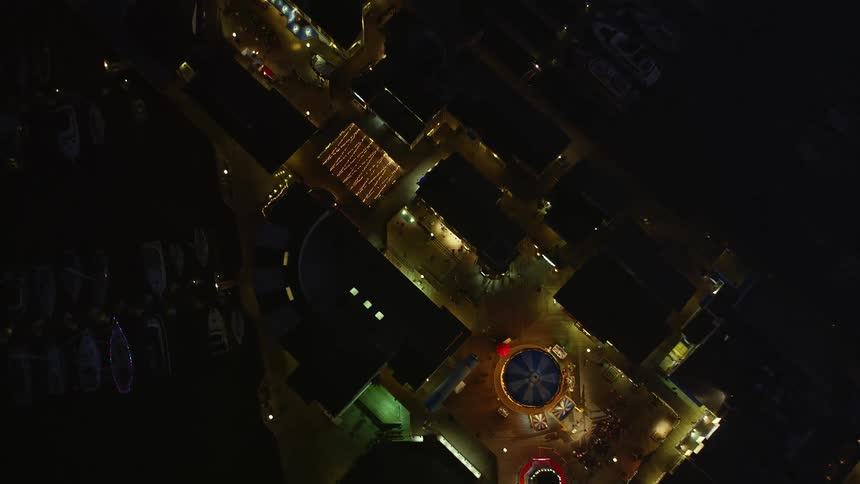 A nighttime aerial view of a litup plaza surrounded by buildings in the city