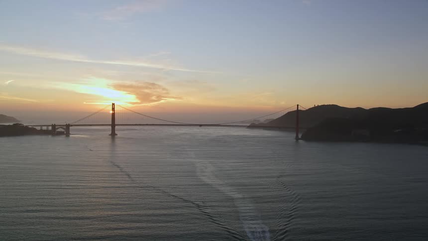 A boat moves across a bay near a bridge