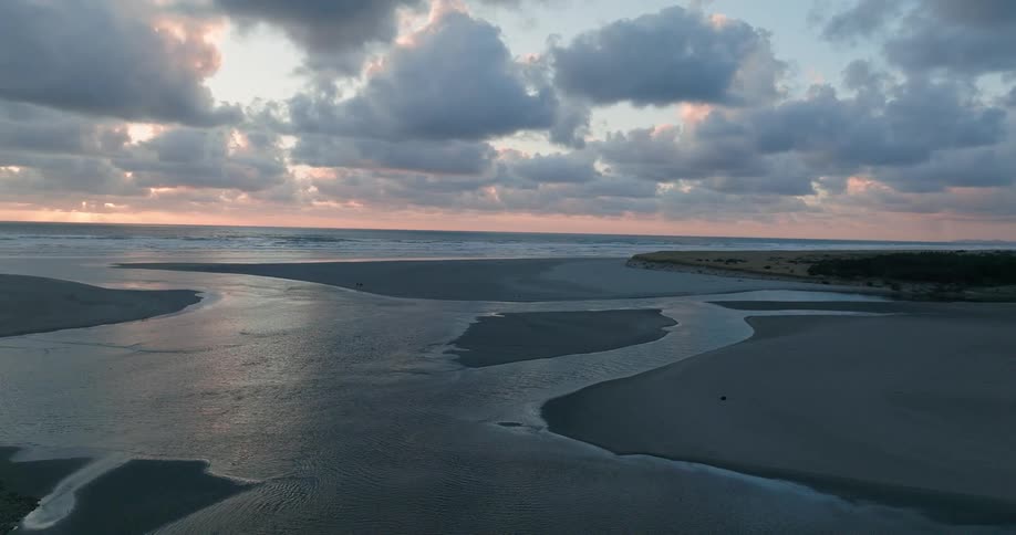 A serene beach at dusk with calm waters and a cloudy sky