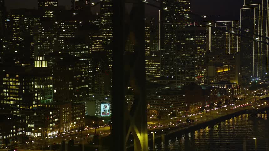Traffic crosses suspension bridge near downtown at night