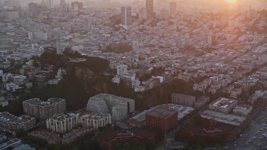 An aerial view captures the densely packed buildings of san francisco with a large green hill at the center