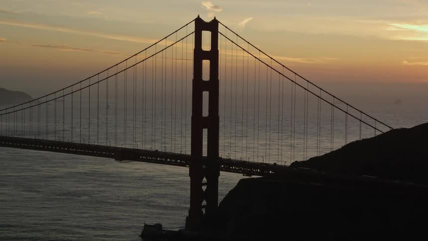 The orange hues of the setting sun bathe the golden gate bridge in a warm light
