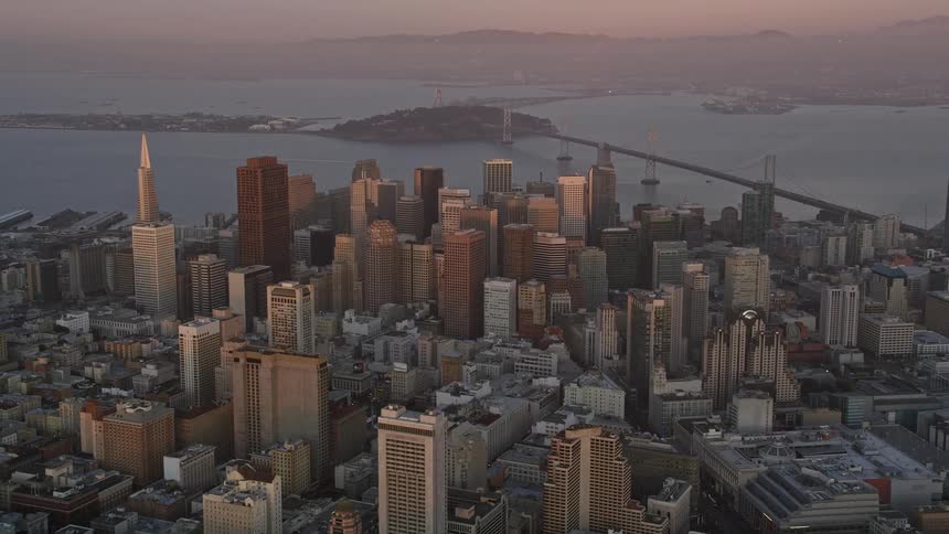 Aerial view showcases san franciscosdense cluster of skyscrapers bathed in the warm glow of the setting sun