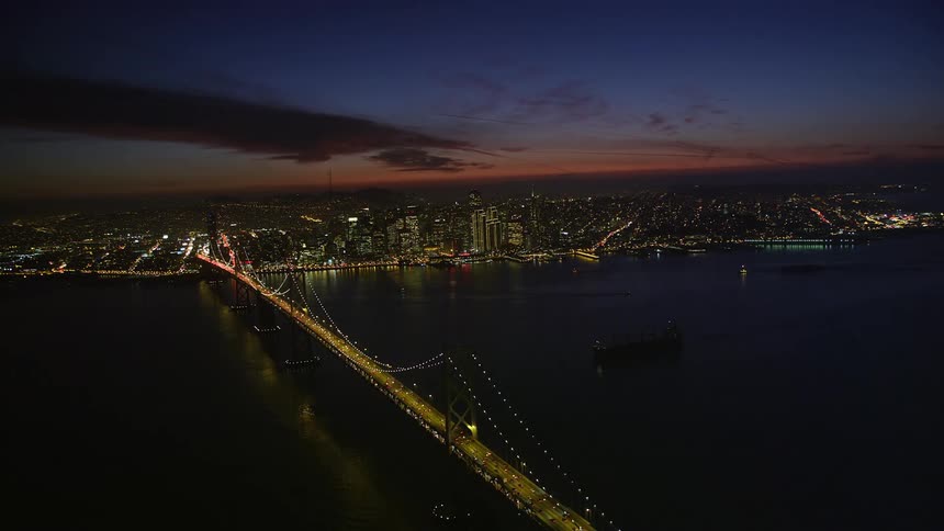 Aerial view of a bridge and city illuminated at dusk