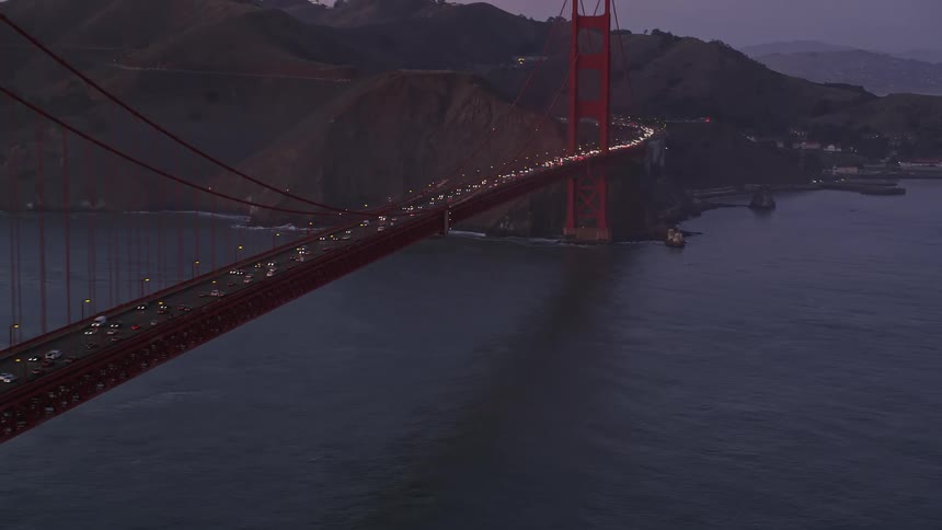 Heavy traffic crossing the golden gate bridge with mountains in the distance