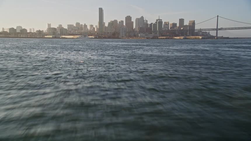 Blue and calm sea and in the background a metropolis with a skyscraper and an extensive bridge