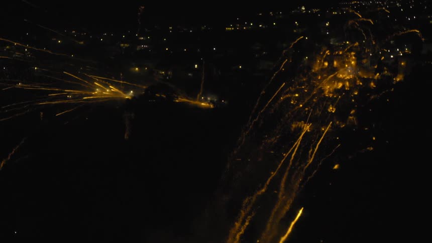 Fireworks firing all over in a night sky over a town