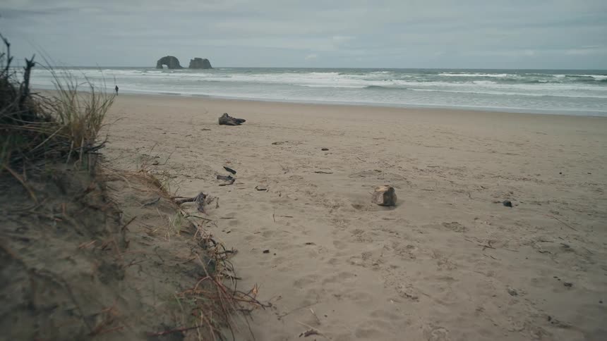 A person walks on a beach as waves crash on shore