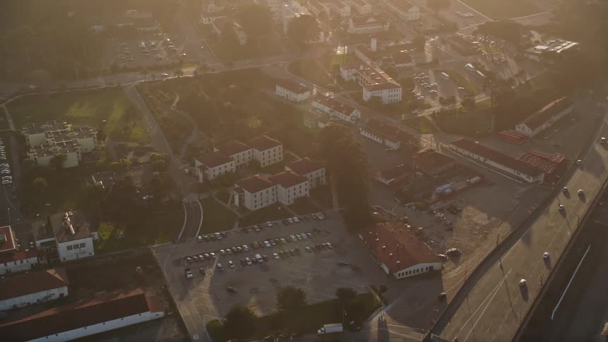 Aerial panorama of highways and intersections in an urban city by the sea with late afternoon solar flare