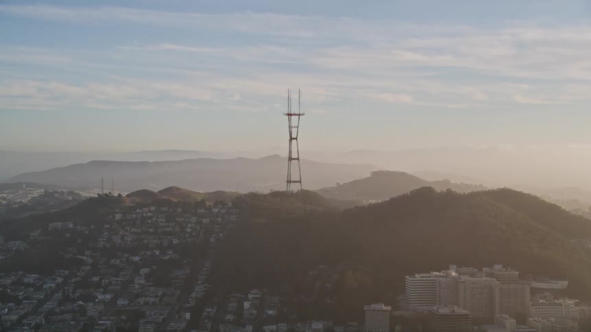 Aerial view in a morning with an urban city surrounding hills and mountains with a broadcast antenna