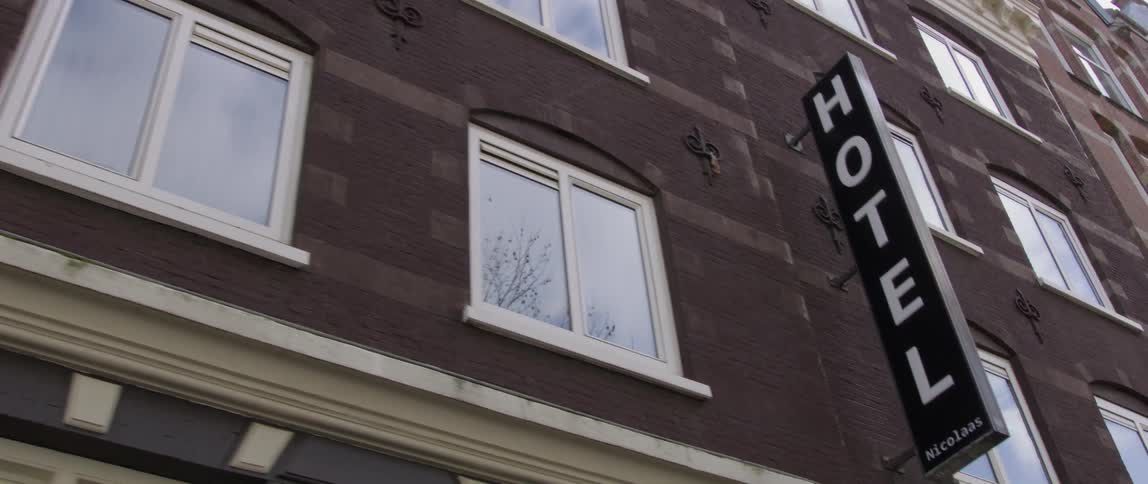 Hotel windows reflect nearby trees and the cloudy sky