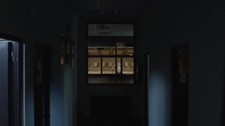 A hallway with a window overlooking a field with two people inside