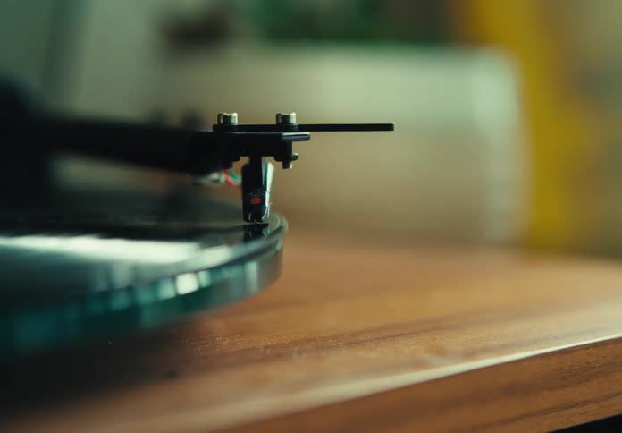 Hand placing the needle on a vinyl record on a vintage turntable