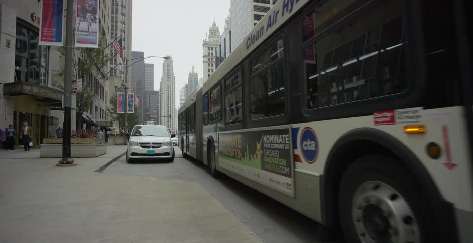 A large white bus with red and blue details is parking next to the sidewalk