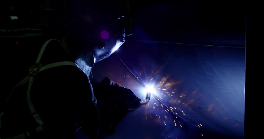A person with equipment is welding on metal and is making a lot of sparks