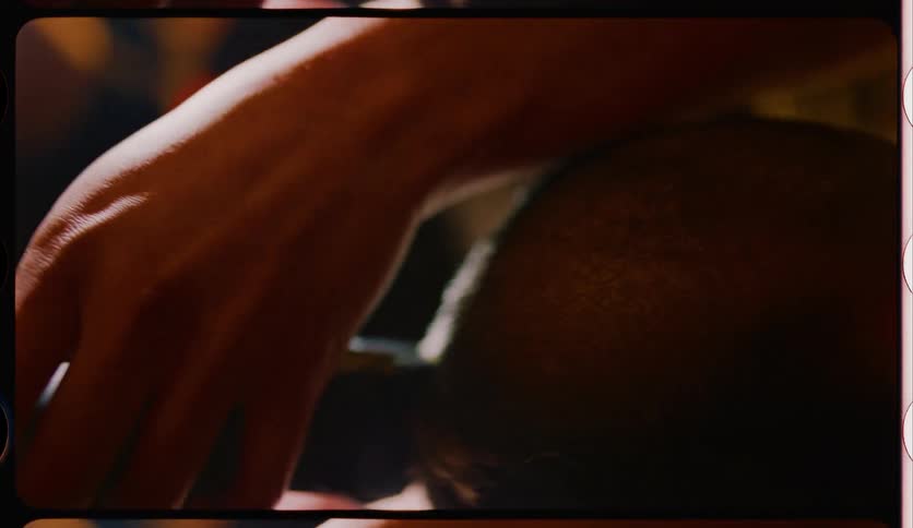 A barber shaving and styling the hair of a balding person