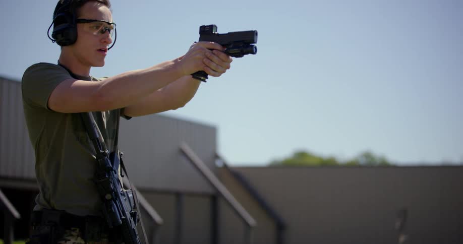 A man shooting a rifle and a handgun in a shooting range