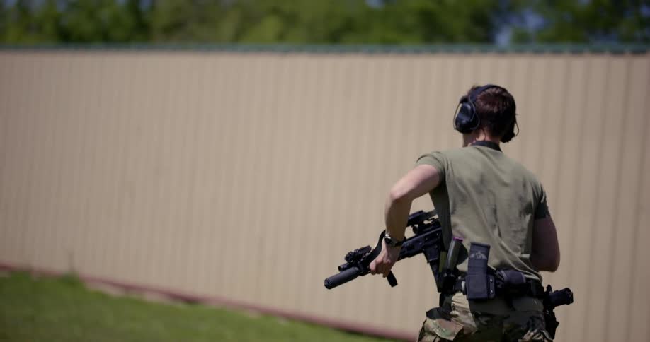 A man in tactical gear runs while holding a rifle