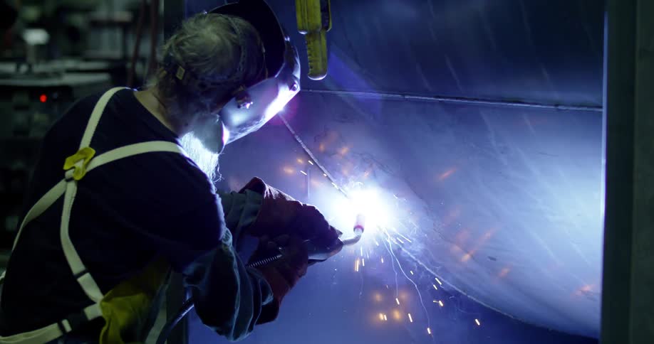 Man with a protective mask welding on a metal platform