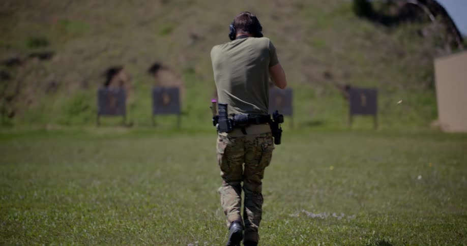 A person with his back turned is walking forward while practicing shooting at a shooting range