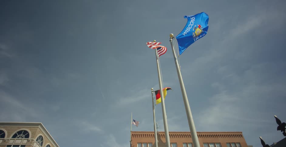 Flags including the us and wisconsin state flags fly on poles